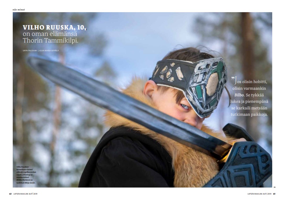 Vilho Ruuska, 10 vuotta, turkiskauluksisessa takissa ja taisteluvarusteissa. Hän kurkistaa miekkansa takaa.
