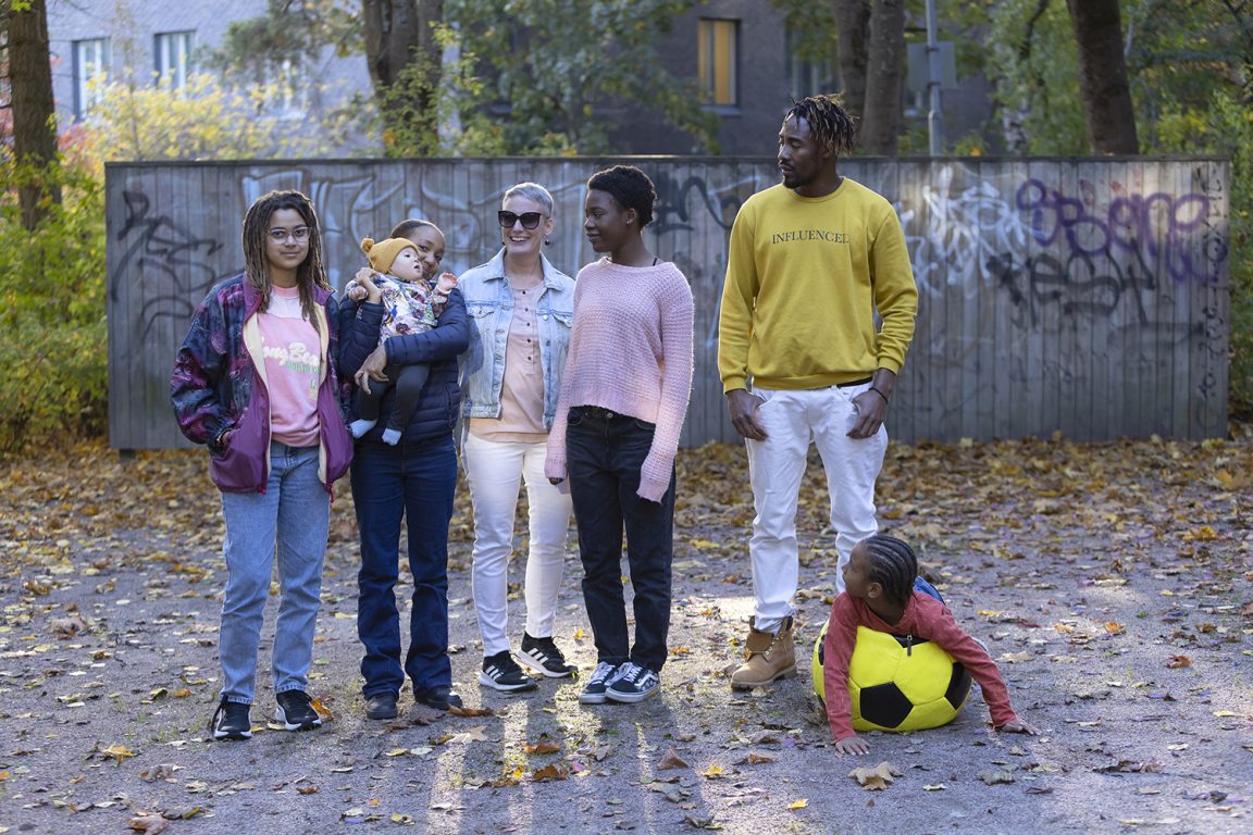 7-henkinen, monikulttuurinen perhe poseeraa puistossa kameralle.